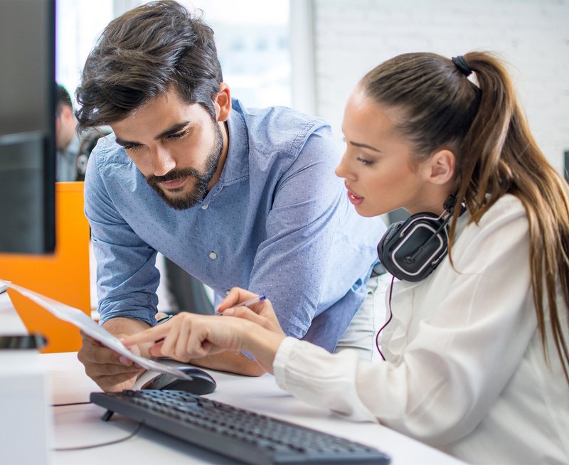 Zwei Mitarbeitenden besprechen sich am Arbeitsplatz